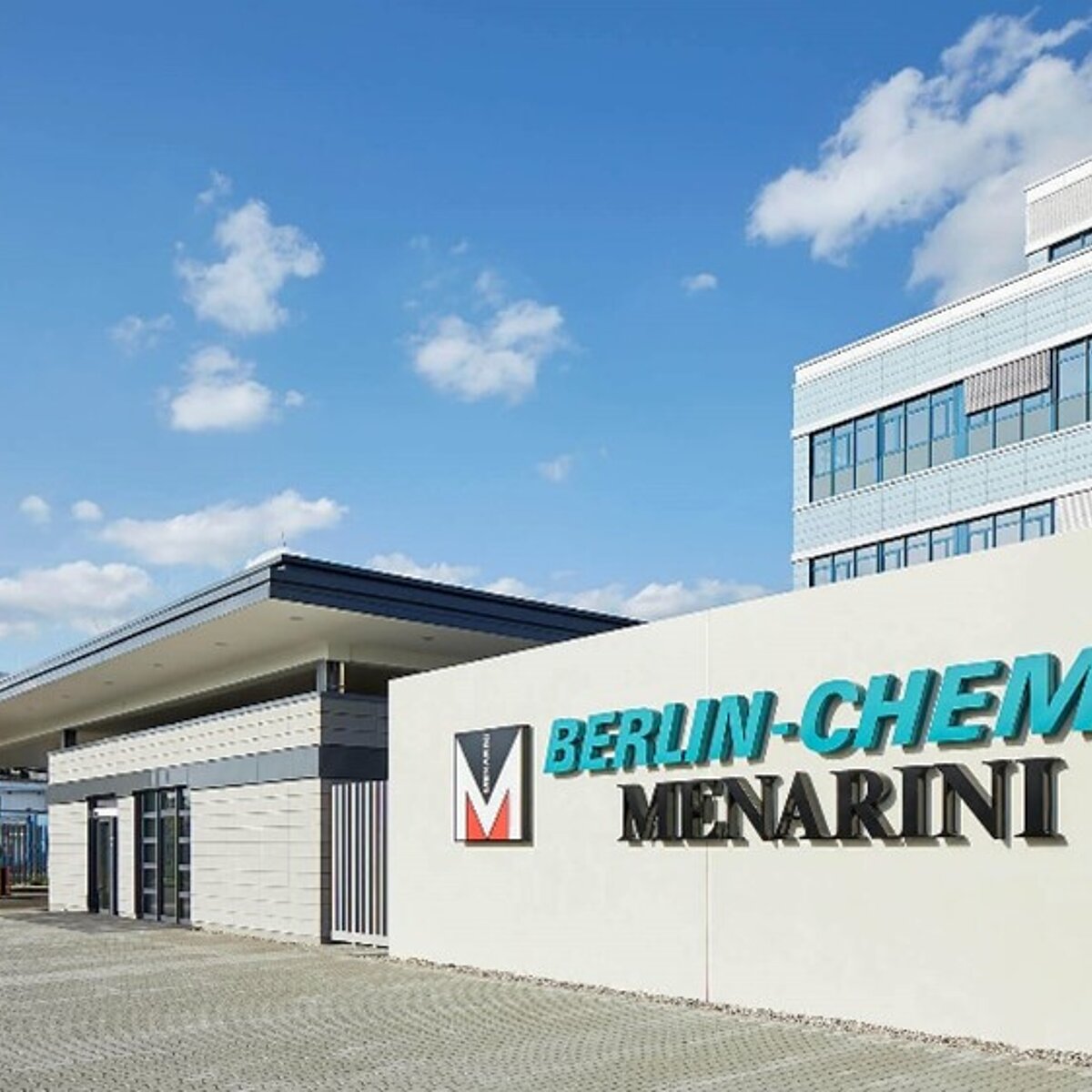You can see the entrance gate and a part of the main building of Berlin-Chemie, a Berlin pharmaceutical company, the logo of the company is placed at the entrance, in turquoise letters.