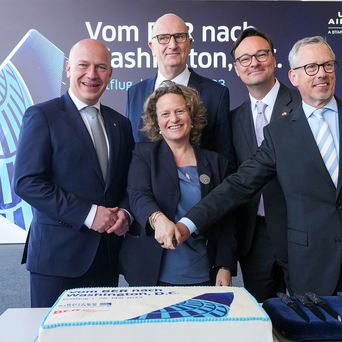 Ceremonial cake cutting for the inaugural United Airlines flight to Washington D.C. with the following people: Kai Wegner, Governing Mayor of Berlin; Aletta von Massenbach, Chairwoman of the Management Board of Flughafen Berlin Brandenburg GmbH; Dr. Dietmar Woidke, Minister President of the State of Brandenburg; Parliamentary State Secretary Oliver Luksic, Member of the Bundestag for the Federal Minister of Digital Affairs and Transport; Thorsten Lettnin, Director Sales Continental Europe, Middle East, Africa, India and Israel, United Airlines.