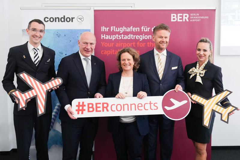The following individuals are holding signs with "#BERconnects" in front of a BER promotional banner: Kai Wegner, Governing Mayor of Berlin, Aletta von Massenbach, Chairwoman of the Management Board of Flughafen Berlin Brandenburg GmbH, and Peter Gerber, Chief Executive Officer of Condor Flugdienst GmbH (from left to right, with the crew).