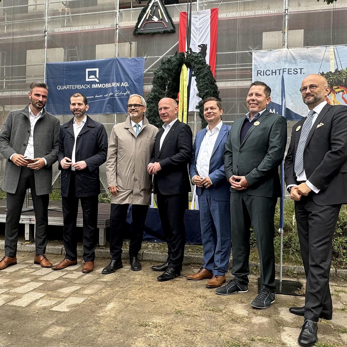 Press photo of the topping-out ceremony with various people including the Governing Mayor of Berlin, Kai Wegner, and the District Mayor of Berlin-Lichtenberg, Martin Schaefer