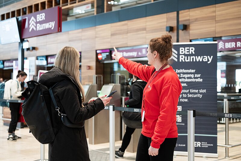 Passenger with a BER employee in front of the BER Runway - Security check on the news topic: BER wins Airport Innovation Award 2023