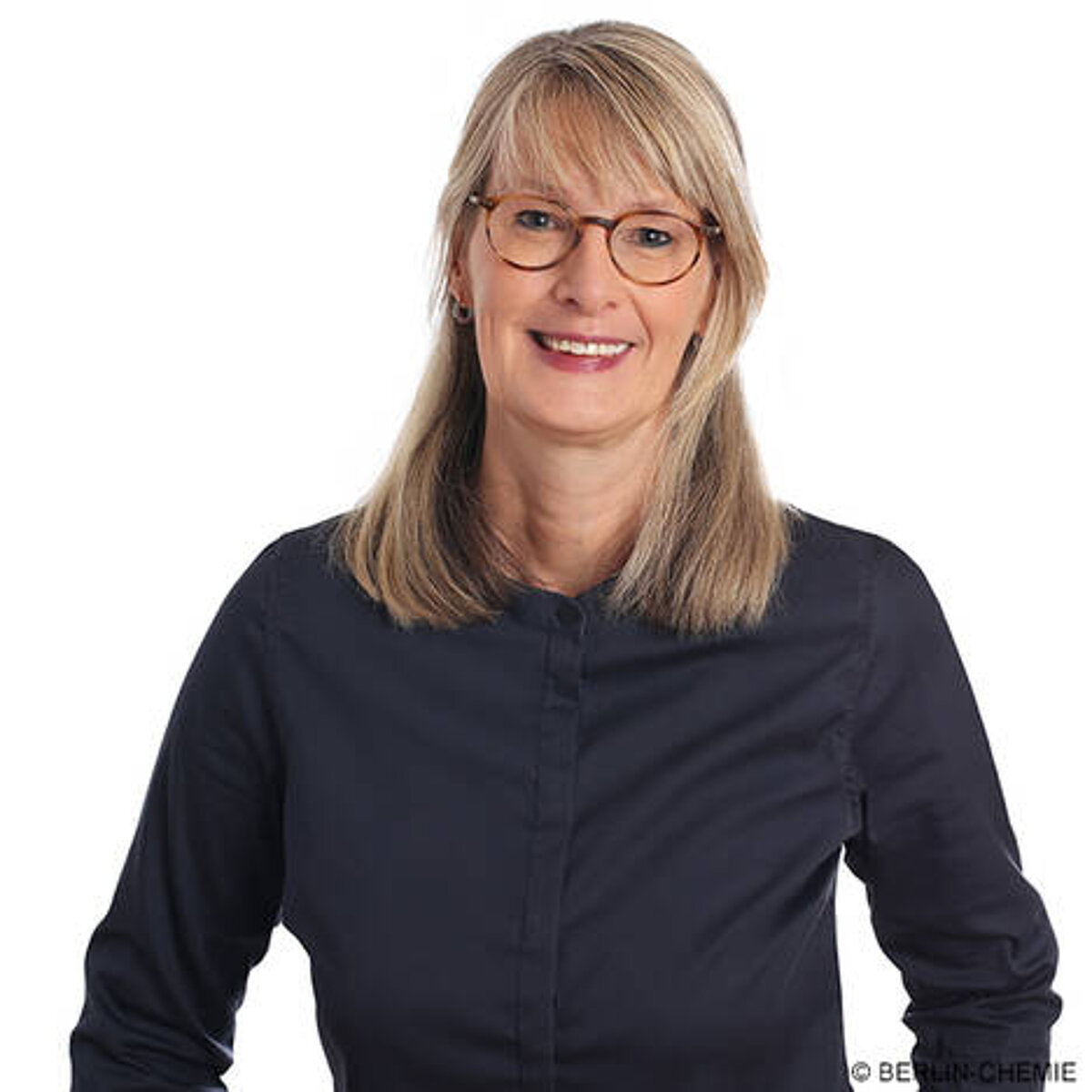 Portrait of Christiane von Eltz, member of the Board of Management at Berlin-Chemie. She is blond, wears glasses, a black blouse and smiles friendly.