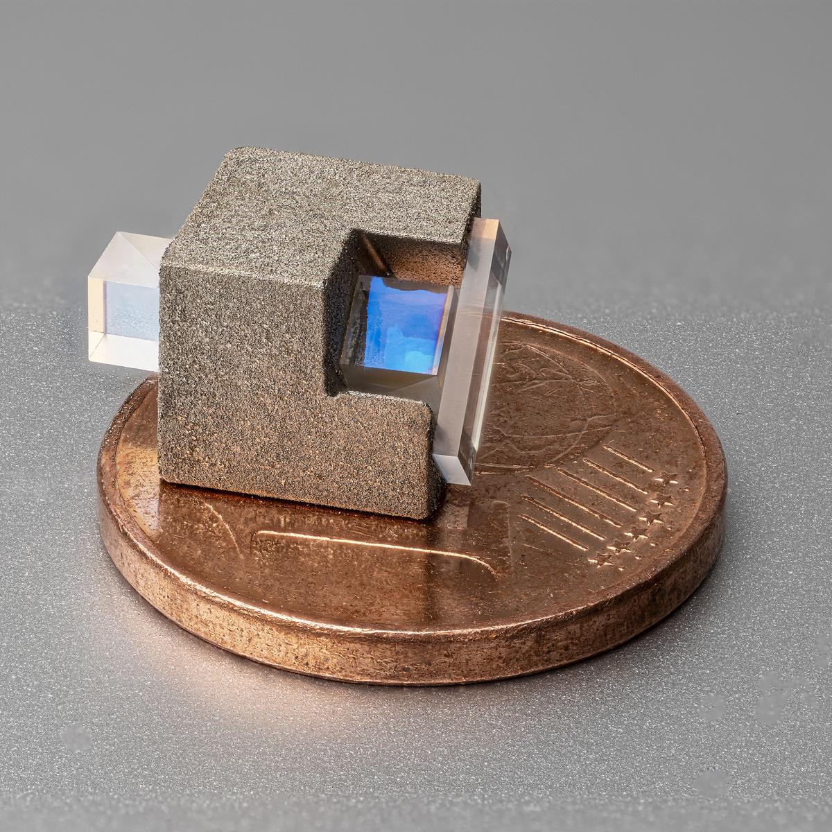 Photo of a miniaturized optical isolator with 30 dB isolation for the wavelength range of 400 to 950 nm, shown in size comparison with a one-cent coin.