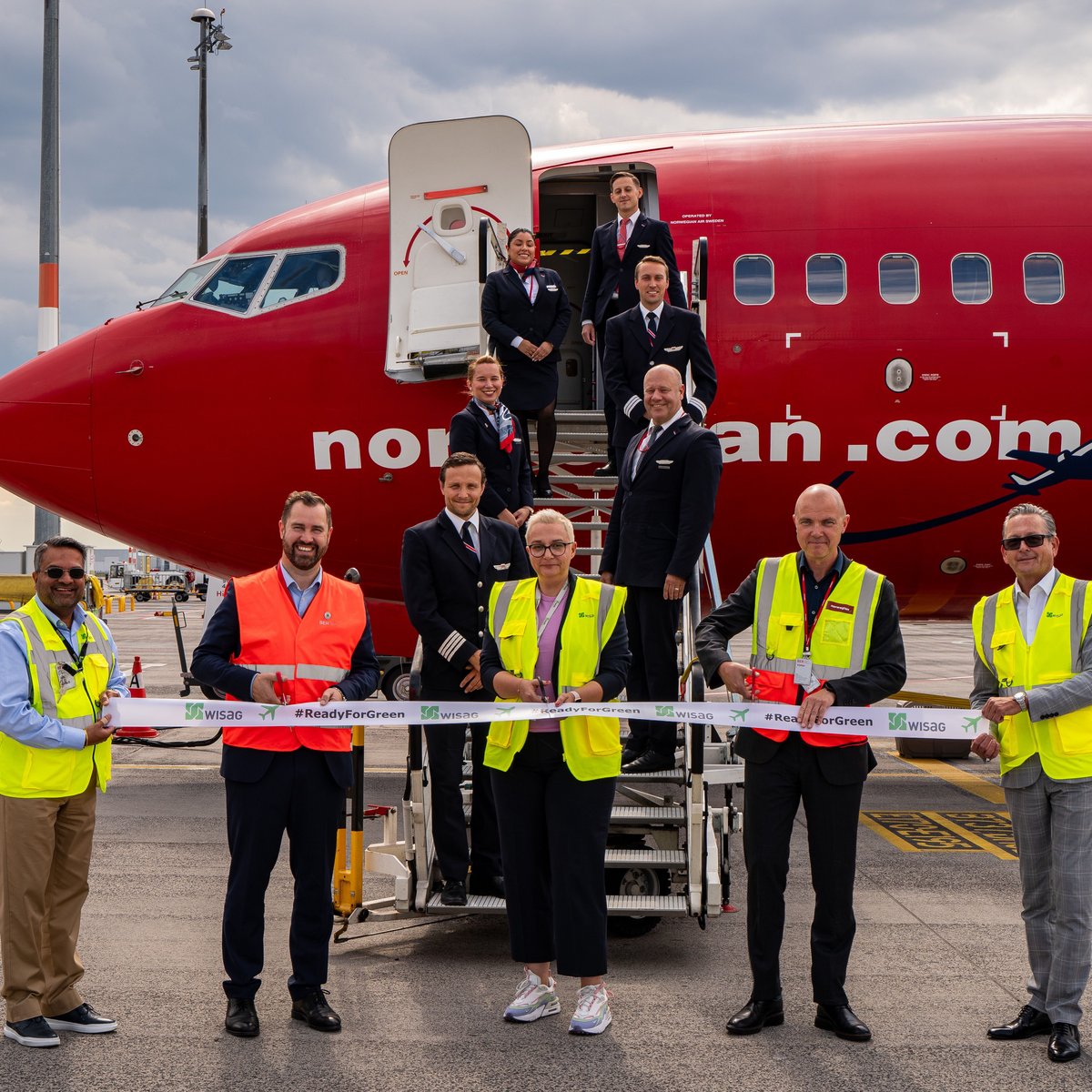 Press photo of "Ready for Green" at Berlin-Brandenburg Airport on the tarmac with various people in front of an airplane