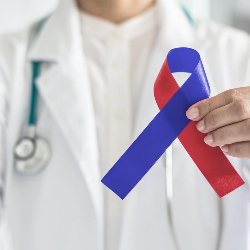 Doctor with stethoscope holding a charity ribbon in red and blue.