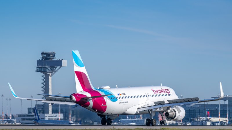 Eurowings aircraft on the apron at BER, with the control tower in the background.
