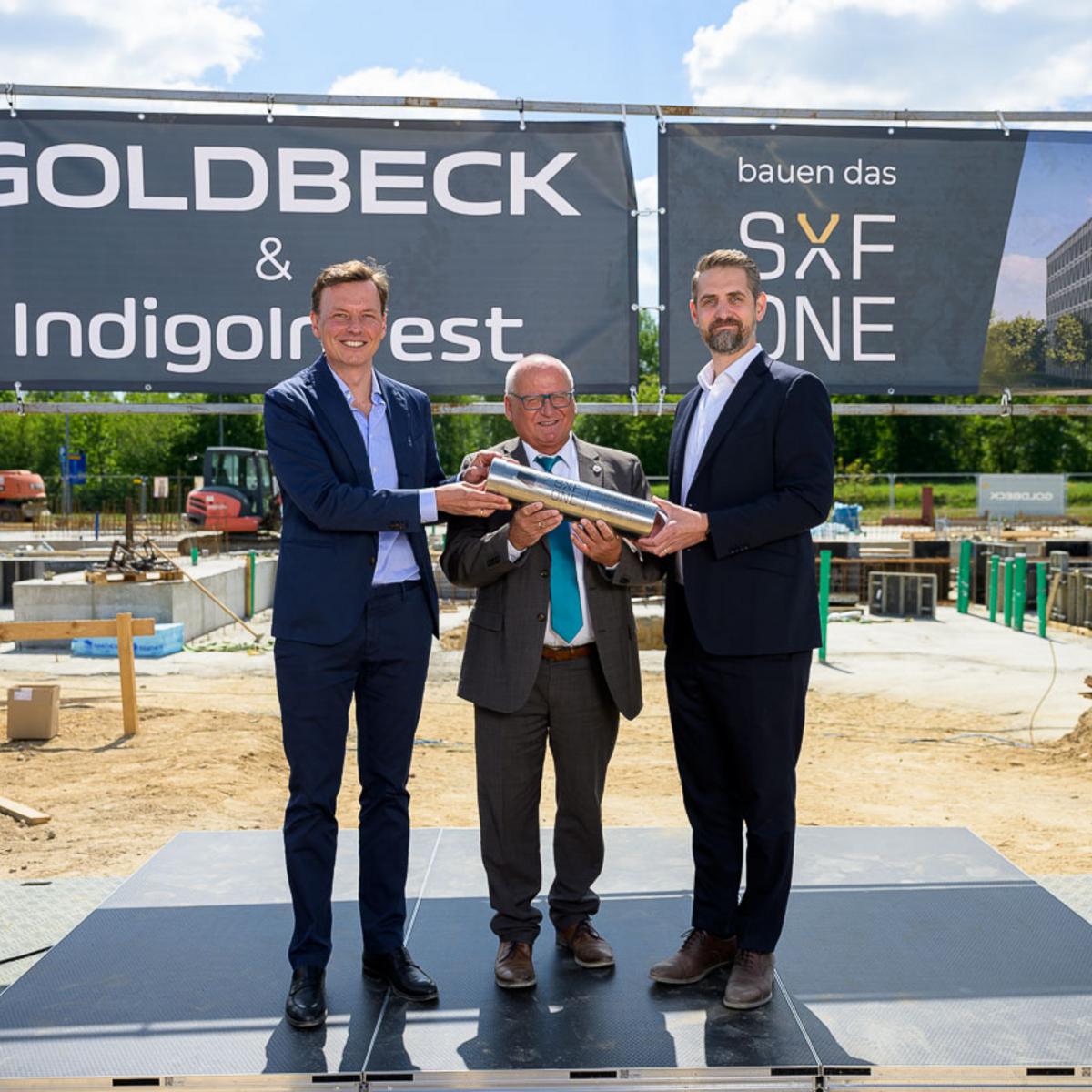 The following individuals held the time capsule for SXF ONE together during GOLDBECK’s breaking ceremony in Schönefeld: Eric Reichardt (Investment Manager at Indigo Invest), Schönefeld’s Mayor Christian Hentschel, and Goldbeck Branch Manager Benjamin Schmidt.