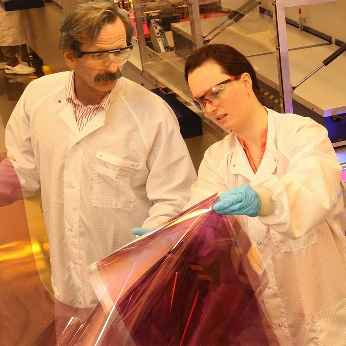 The picture shows two researchers in the laboratory holding and examining thin solar modules.