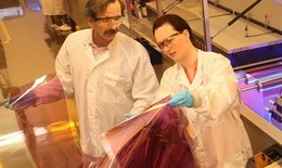 The picture shows two researchers in the laboratory holding and examining thin solar modules.